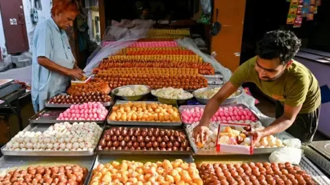 AFP via Getty Images An image of a sweetmeats shop in northern India showing a wide array of desserts